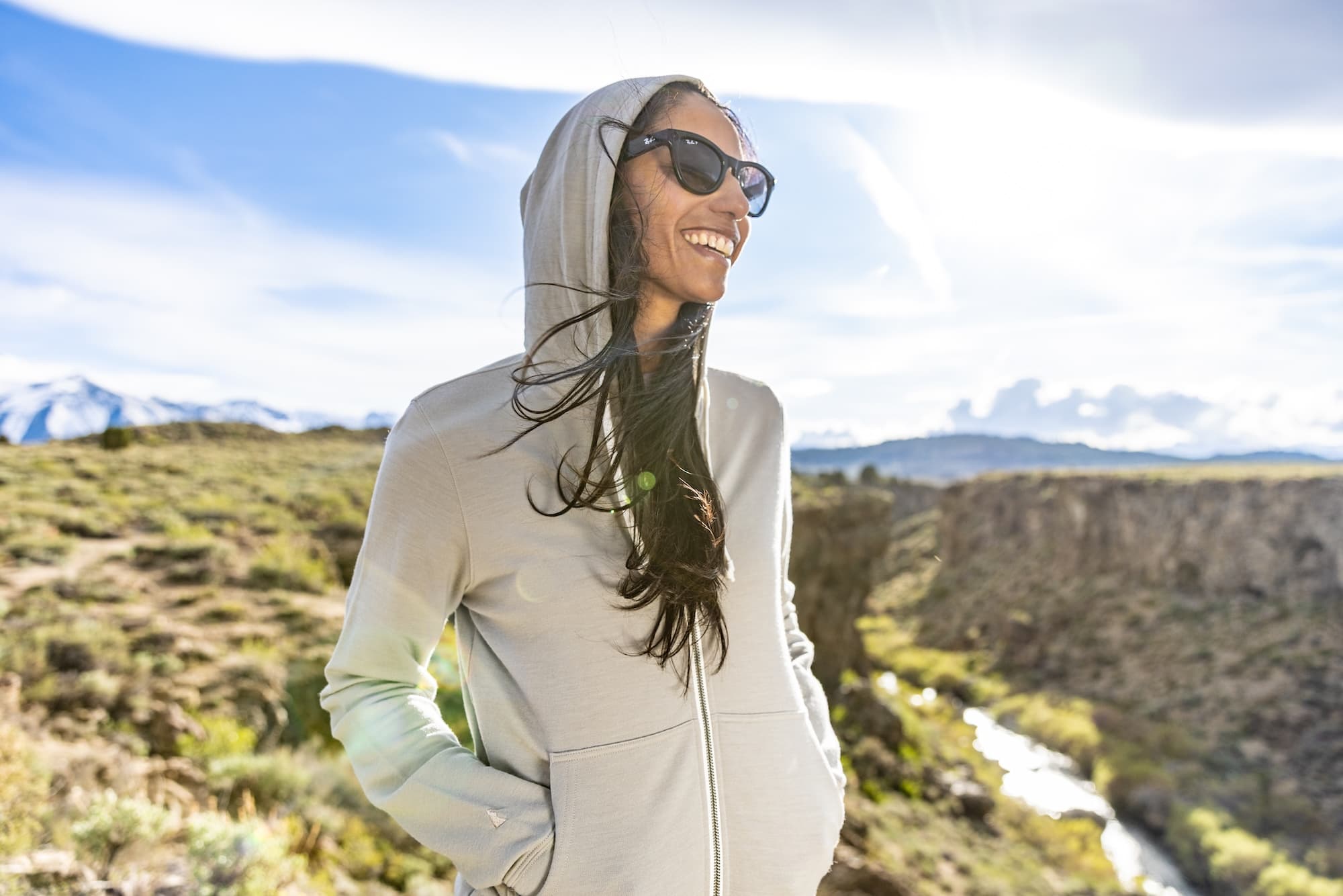 a woman smiles wearing a gray Traveler Hoodie