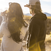 a couple looks out at mountain views wearing Traveler Merino Hooodies