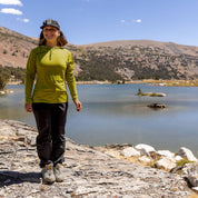 a hiker smiles wearing a Golden Lime Ridge Merino Solstice Sun Hoodie