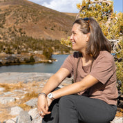 a woman smiling sitting on a rock during a hike in a Merino Wool Oversized Tee