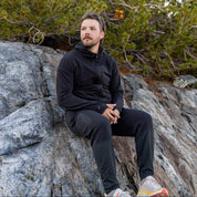 a backpacker wearing a Cloudripper Full Zip Hoodie and Cloudripper joggers sitting on a rock
