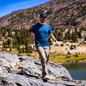 a man walking on a rocky trail wearing a Journey Merino Wool T-Shirt in Sailor Blue