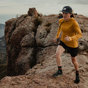 a woman going trail running wearing the Ridge Solstice Sun Hoodie in Goldenrod