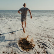 a man wearing Ridge underwear and a Ridge tee runs into the ocean