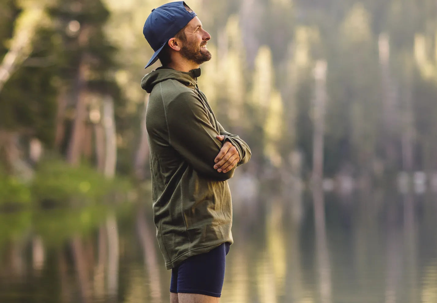 a man wearing Ridge Merino boxer briefs stands by a backcountry lake