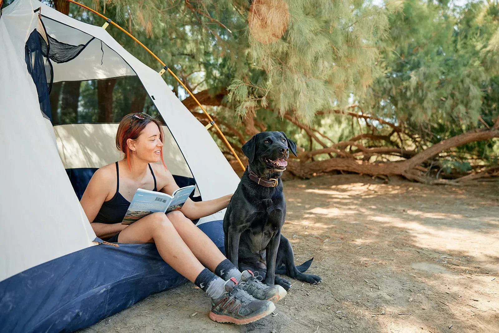 a woman sits in a tent reading with her dog wearing a Ridge Merino bralette