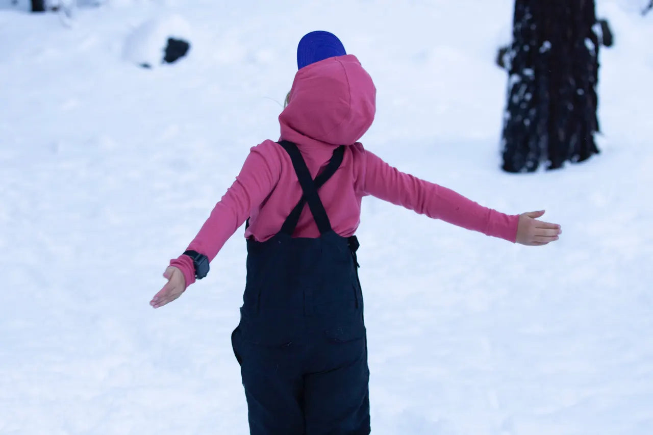 a girl plays in the snow wearing a Ridge Merino base layer