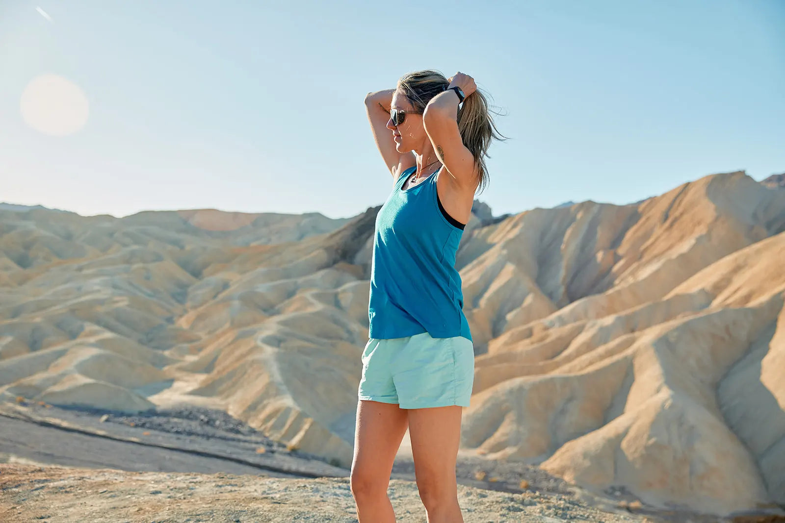 a woman wearing a Ridge Meirno tank top in Death Valley puts her hair up in a ponytail