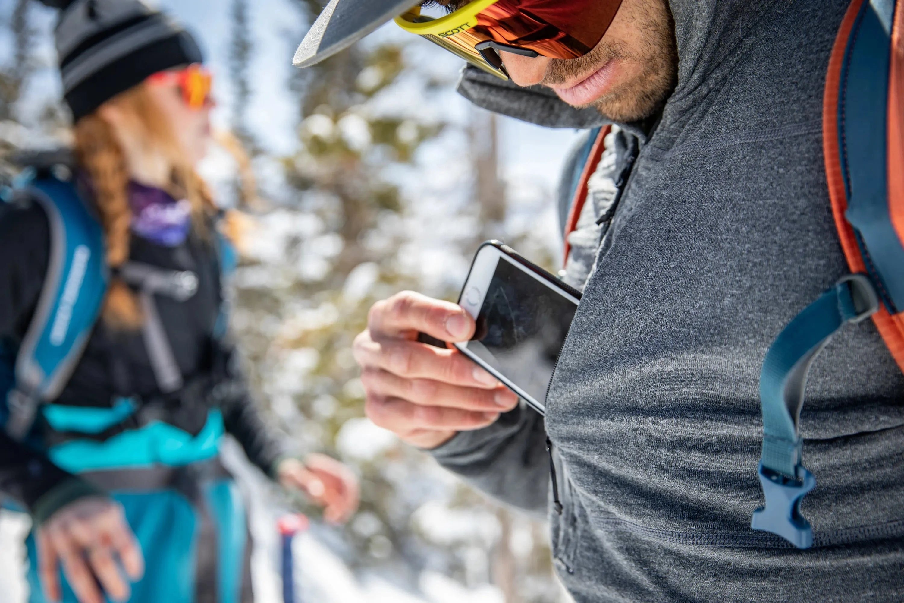 a man pulls a phone out of the pocket of his Convict Canyon Mid Layer Hoodie