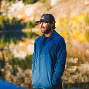 a man smiles by a lake wearing a Hyde Merino Hoodie
