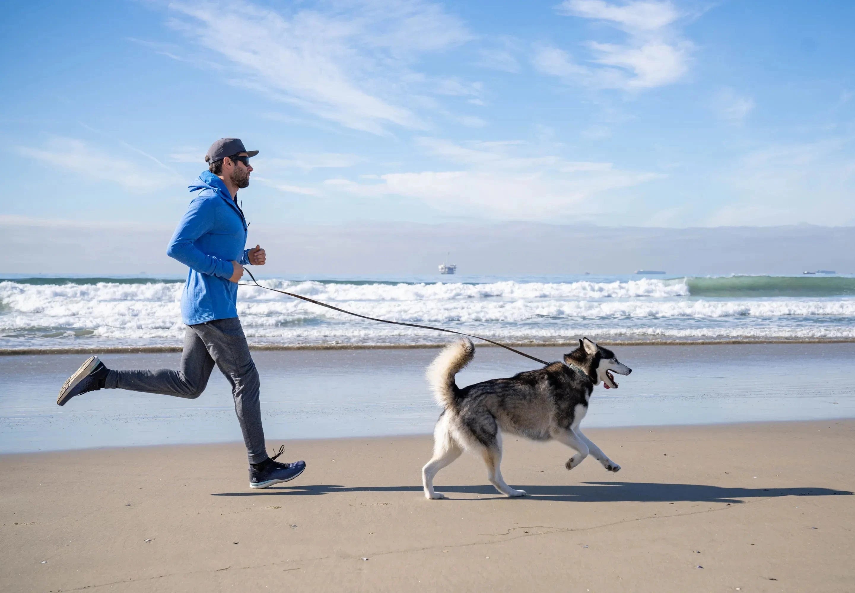 a man goes for a run with his dog on the beach in Southern California wearing the Convict Joggers
