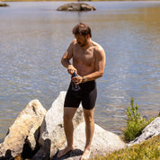 a man filters water in his boxer briefs at an alpine lake