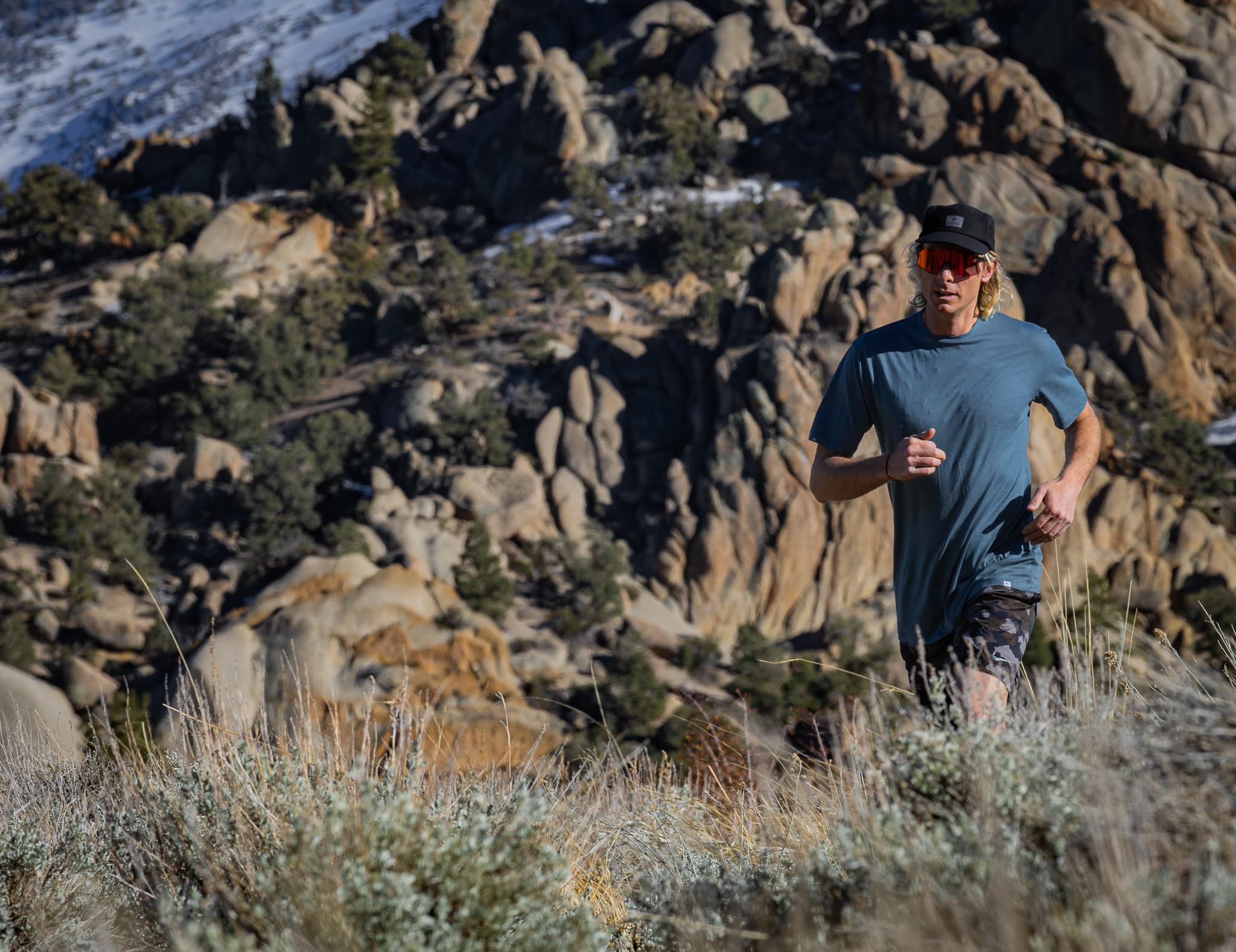 a man running on a rocky trail in a blue Pursuit Ultralight Tee