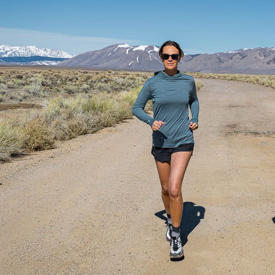 a woman trail running in a Pursuit Ultralight Merino Hoodie