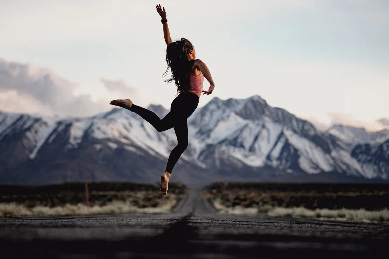 a woman jumps gracefully on a road in Mammoth Lakes wearing Ridge Merino base layers