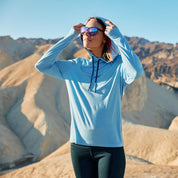 a woman puts up the hood on the Solstice Lightweight Pullover Hoodie