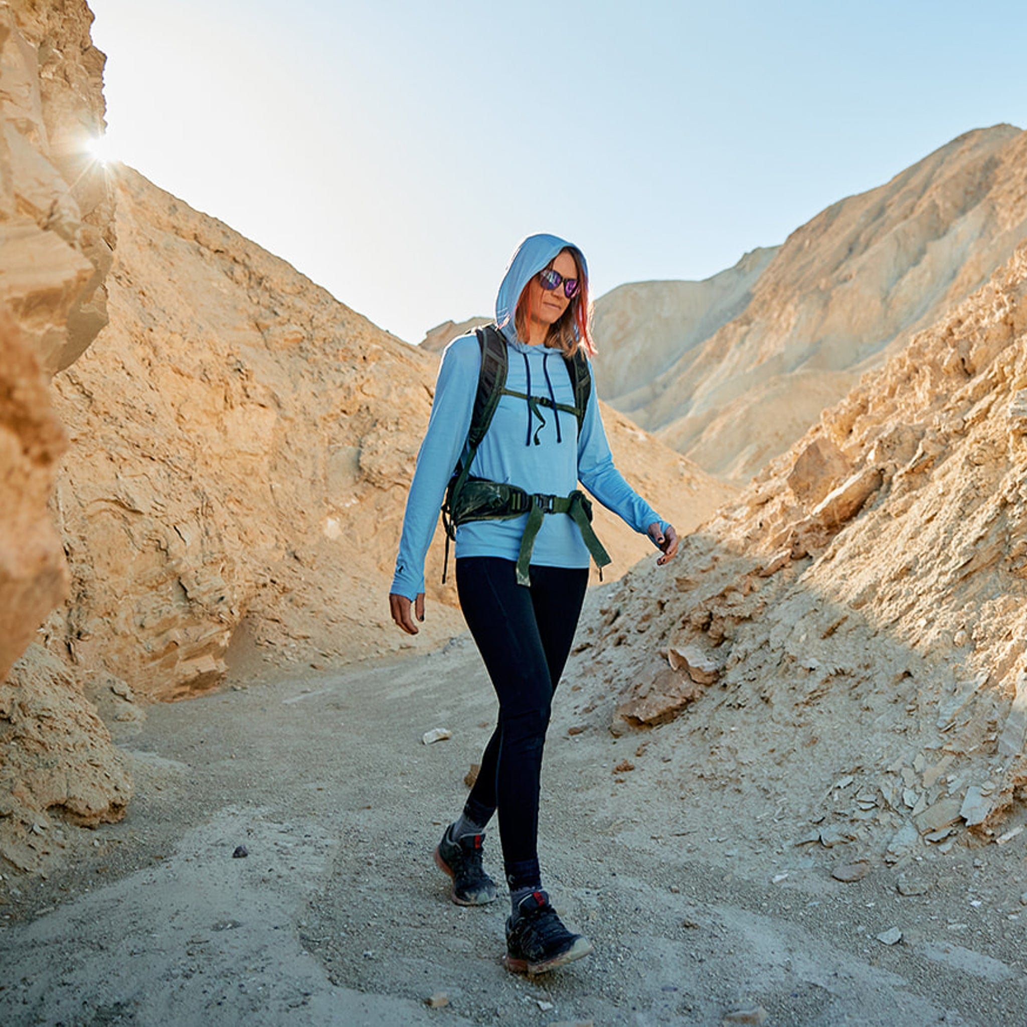 a woman hikes through a Death Valley canyon in the Solstice Sun Hoodie