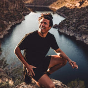 a man wearing the Journey Merino tee and shorts by a creek