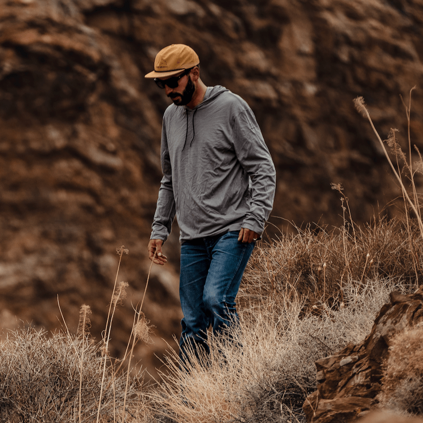 a man on a hike wearing a Solstice Hoodie and Ridge Merino hat