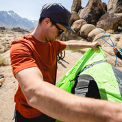 a man sets up a tent in the desert wearing a Journey Merino T-Shirt