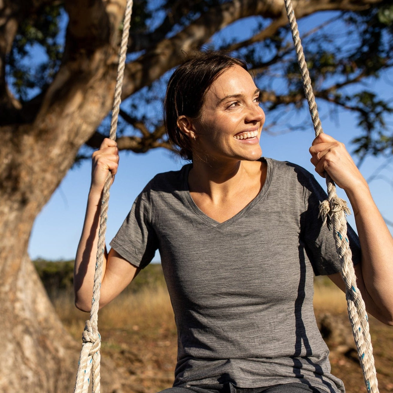 a woman wearing a Wander V-Neck T-Shirt on a swing under a tree