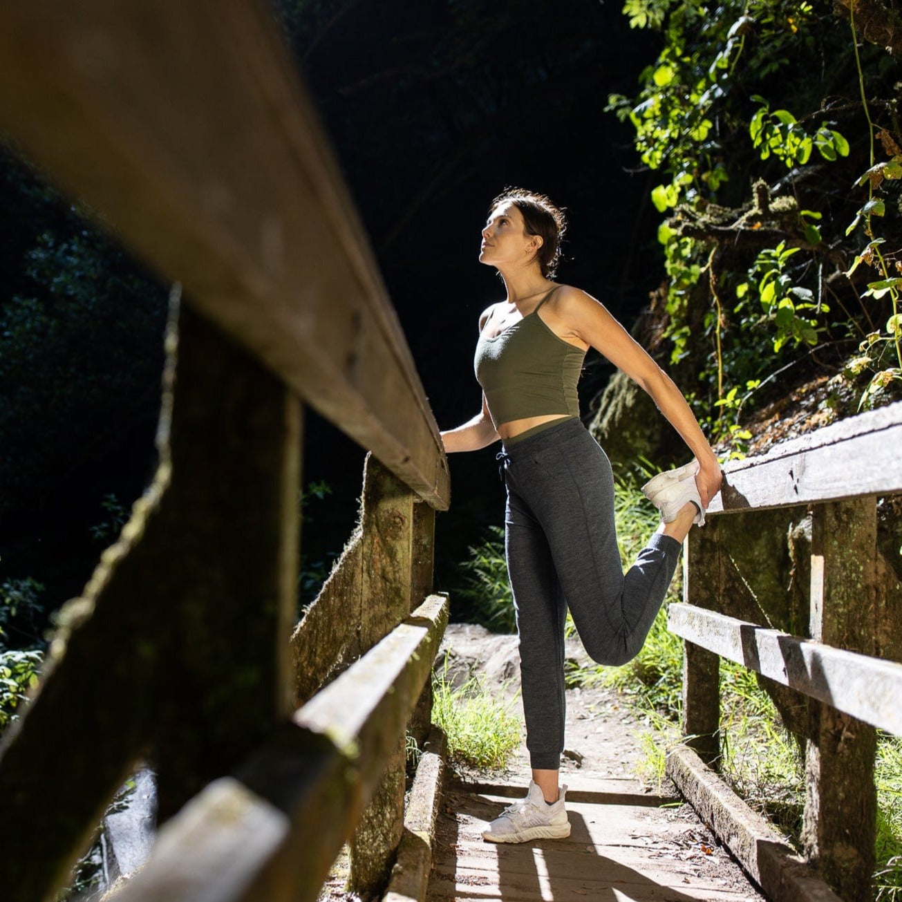 A woman stretches on a trail run wearing the Women's Merino Wool Bralette