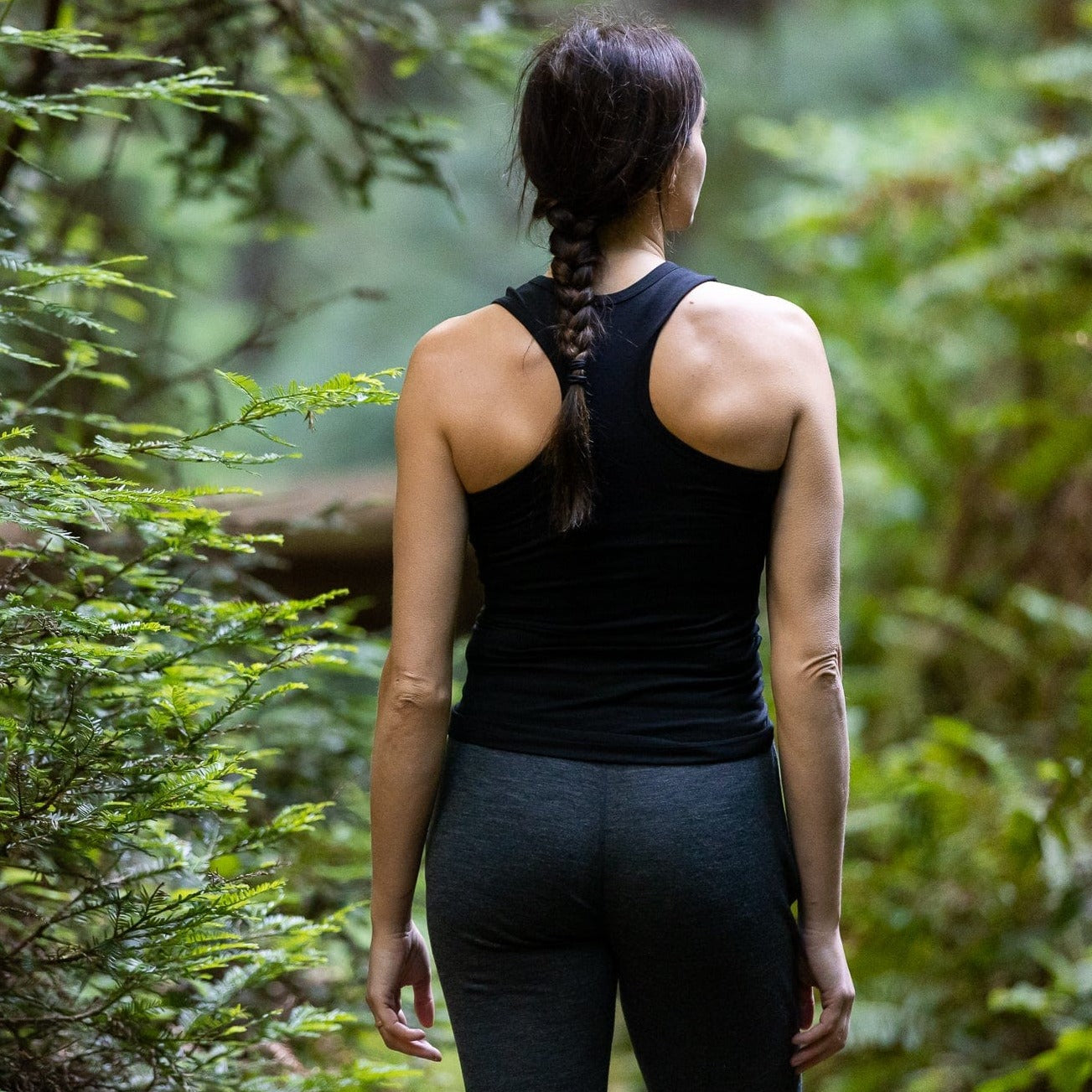a woman wearing a Black Ridge Racerback Tank in a forest