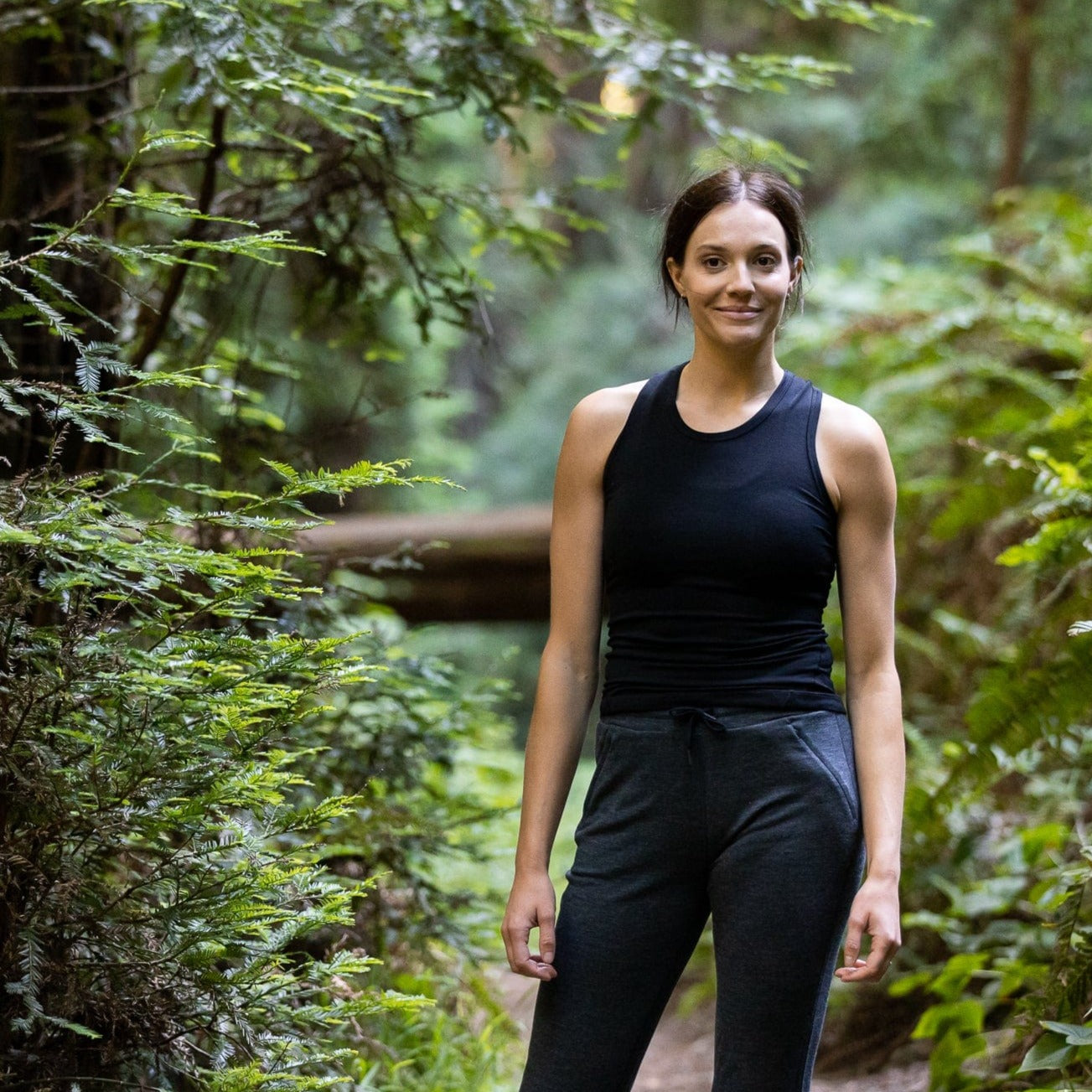 a woman wearing a Black Ridge Racerback Tank in a forest